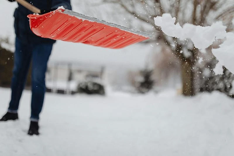 Närbild på hur snö flyger från en snöskyffel.